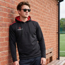 Load image into Gallery viewer, Black and red Heritage Hoodie on a model standing in a sports hall.
