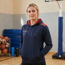 Load image into Gallery viewer, A teacher model standing in a school sports hall wearing a navy and red Heritage Hoodie from Scorpion Sports.

