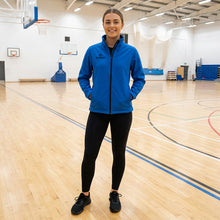 Load image into Gallery viewer, Model wearing a Scorpion Sports Royal Blue Softshell Jacket in a sports hall.
